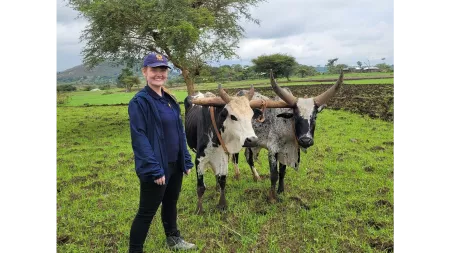 Ethiopia_Sarah Easter standing next to cows in a meadow
