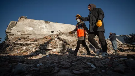Men walking in front of rubble