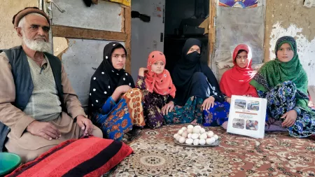 Afghanistan_Family sitting on brown rug with tray of eggs in front of them