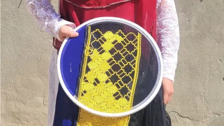 Afghanistan_Woman in blue black and yellow skirt holding embroidery