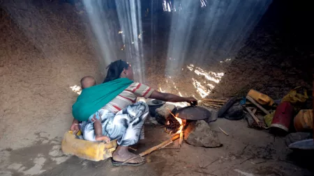 Ethiopia_Woman sitting in hut with light shining through cooking area
