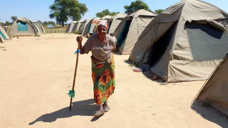 Zambia_Old woman standing between line of tents in displacement camp