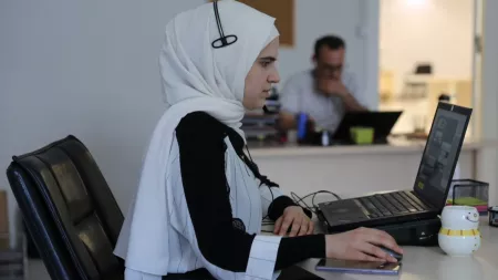 Turkiye_Woman on laptop with mouse and headset in office