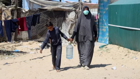 Woman and child carrying gallon of water