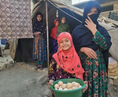 Afghanistan_Little girl hold green dish filled with egges next to veiled woman