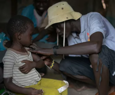 South Sudan_CARE worker in grey shirt kneeling helping small child