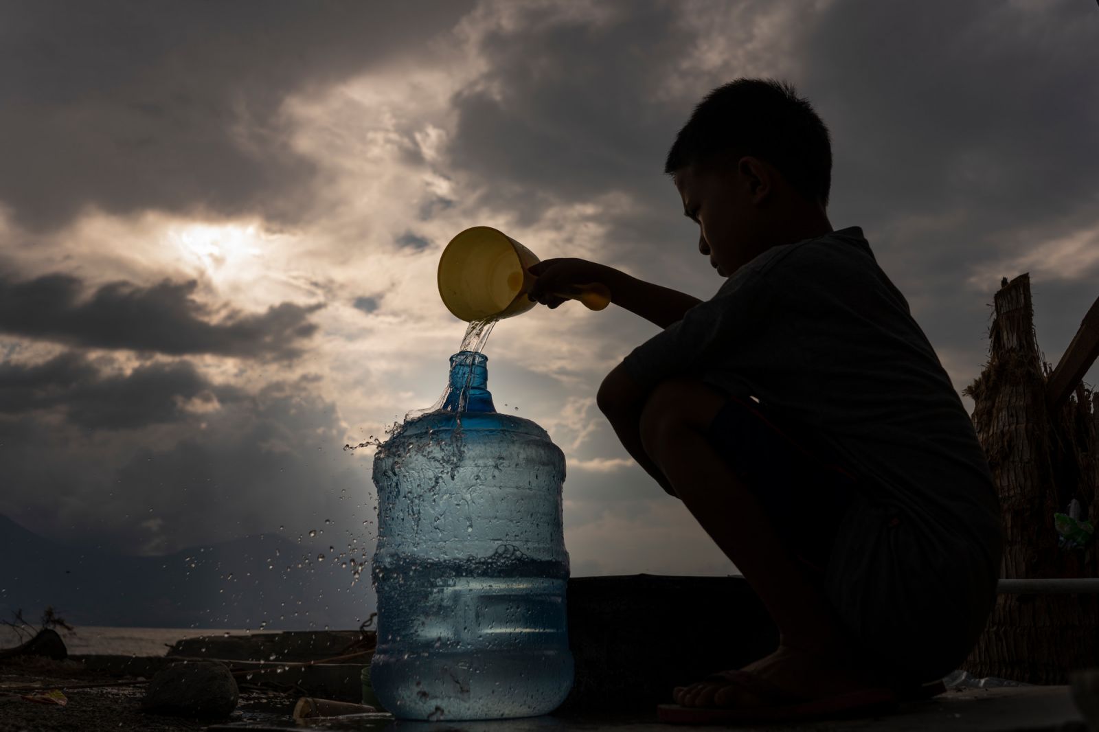 A boy collects water near a temporary shelter for survivors of the earthquake and tsunami. Donggala, Central Sulawesi, Indonesia. October 15, 2018. Credit: Fauzan Ijazah/CARE.