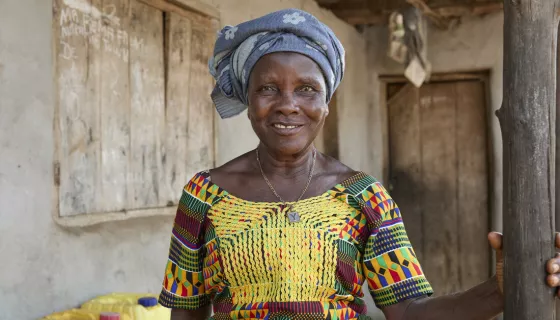 Portrait of woman wearing patterned dress and headscarf smiling at the camera