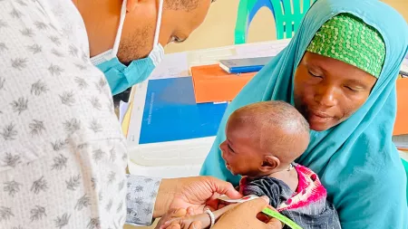 CARE Health Officer Abdikadir Abukar with baby and mother
