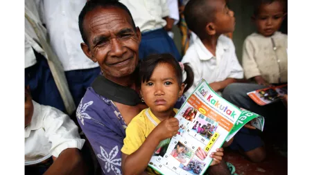 Old East Timorese man and child holding Lafaek magazine