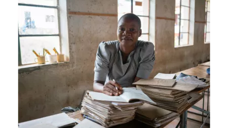 Zimbabwean school teacher with piles of books