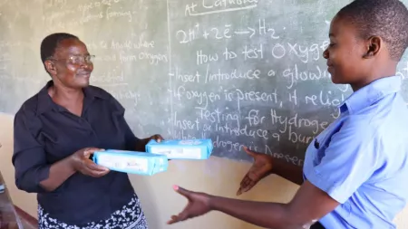 Zimbabwean teacher handing over sanitary products to student