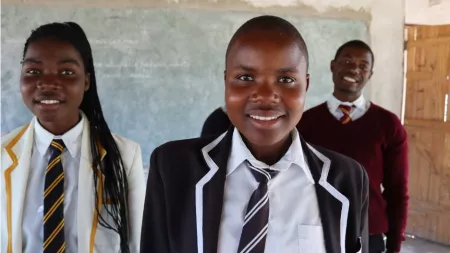 Three Zimbabwean students in uniform smiling