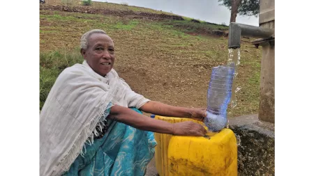 Ethiopia_Older woman pouring water from community tap