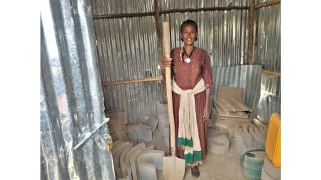 Ethiopia_Woman standing in shack with concrete slabs for stoves