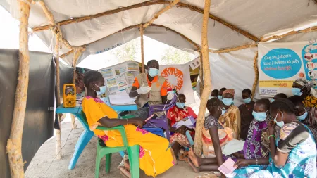 Health professional in the centre speaking with pregnant and lactating women around inside a tent