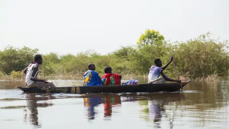 Four people in a canoe crossing a flooded area in South Sudan