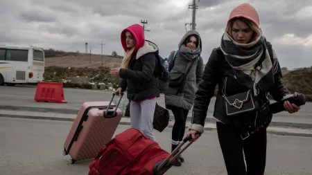 Three women with winter clothes and carrying luggage