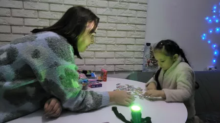 Mother and daughter playing with a puzzle on a table with low light