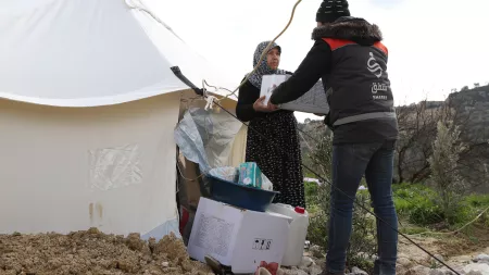 Man giving box to woman in front of tent