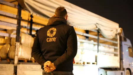 Man wearing CARE's jacket in front of truck