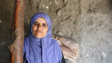 Woman leaning on post wearing blue scarf