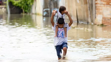 Peru_Little boy with small boy on his shoulders walking through flood