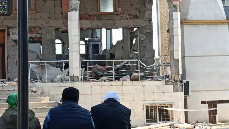 Backs of three people looking at destroyed building front