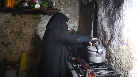Yemen_Woman in black burqa cooking on gas stove