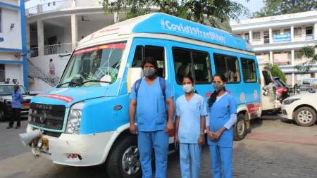 India_Medical care workers standing in front of vaccine van in blue scrubs