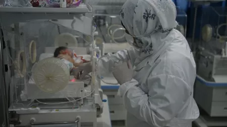 Syria_Dr with hijab on handling newborn in incubator
