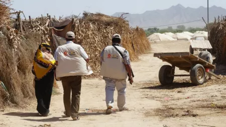 Yemen_CARE Rapid Response team walking with displaced woman in IDP camp