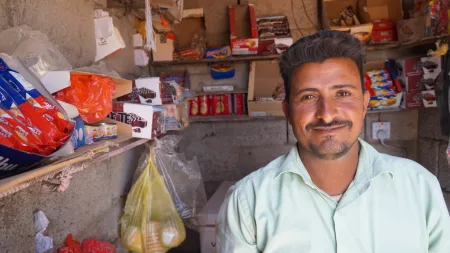 Yemen_Man standing in front of informal shop smiling