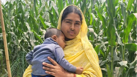 Bangladesh_Woman with yellow sari holding son in front of wheat field