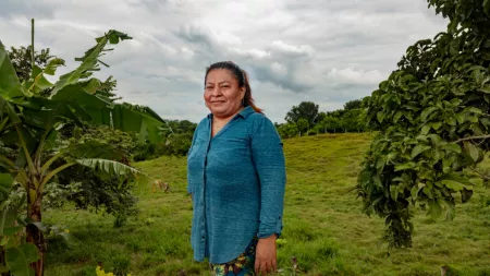 Honduras_Woman in blue shirt standing in front of field