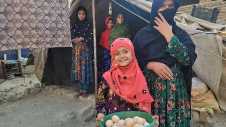 Afghanistan_Little girl hold green dish filled with egges next to veiled woman
