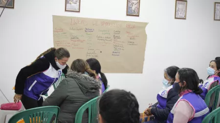 Colombia_Women sitting on green chairs in listening to class with chart in front