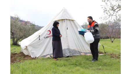 Syria_Woman in black standing outside of tent getting package handed over to her