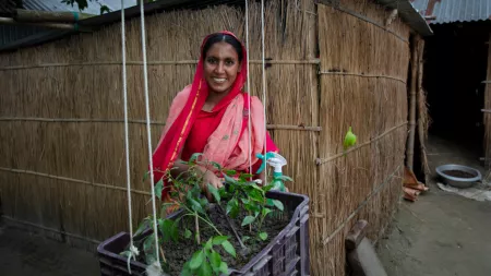 Bangladesh_Woman in red and pink sari smiling by hanging crate garden