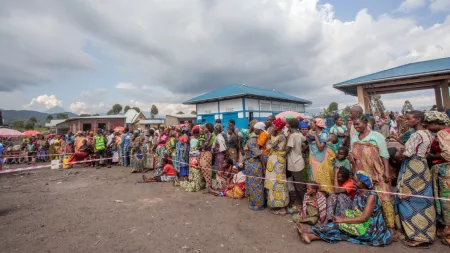 DRC__Women standing in long line marked off by red and white tape in distribution centre