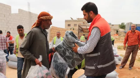 Syria_NGO working handing over blanket to Syrian man