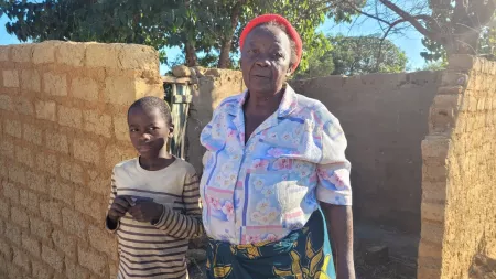 Zambia_Grandmother standing with grandson in front of home under construction