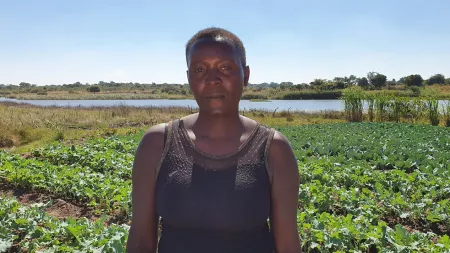 Zambia_Woman in black tank with short hair standing in vegetable garden