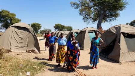 Zambia_Women standing in formation in between displacement camp tents