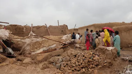 Pakistan_People standing by destroyed home after flood