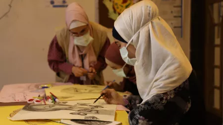 Syria_Girls drawing on paper with woman supervising them