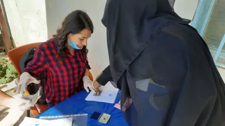 Syria_Sara helping lady in fingerprint registration