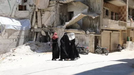 Syria_Three women in black niqabs looking back at destroyed building