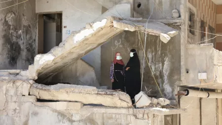 Syria_Women in hijabs standing in the middle of collapsed building