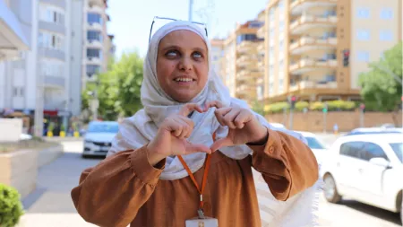 Turkiye_Blind lady with mustard-coloured shirt holding up heart to camera